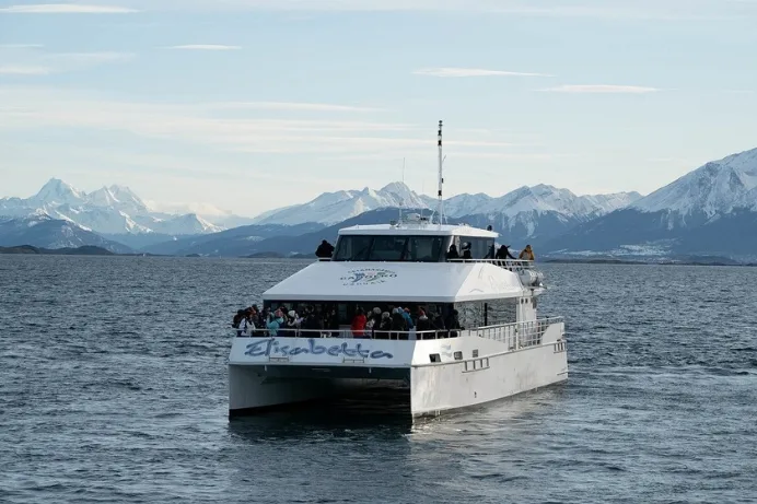 Catamarán "Elisabetta" con pasajeros navegando en el Canal Beagle, Ushuaia, frente a montañas nevadas.