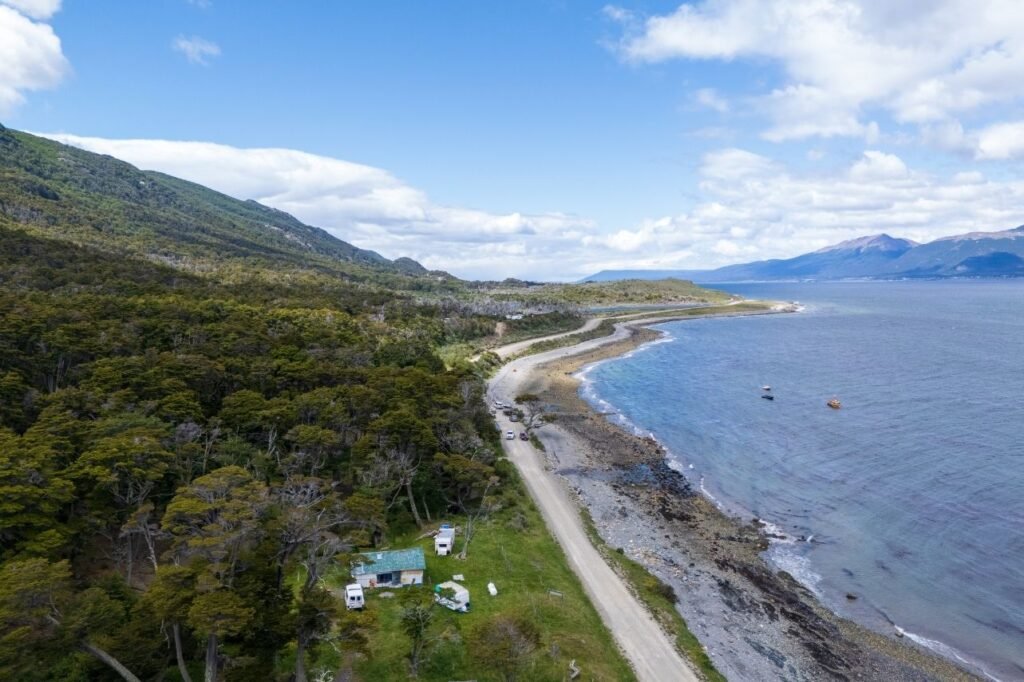 Vista aérea con drone de la costa de Puerto Almanza, el Canal Beagle y la ruta de ripio entre bosques, Ushuaia