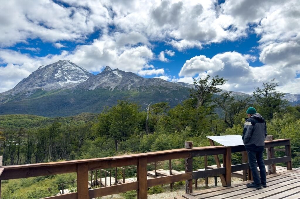 Visitante en el Mirador Cerro Cornú observando montañas nevadas y bosque fueguino, Tierra del Fuego