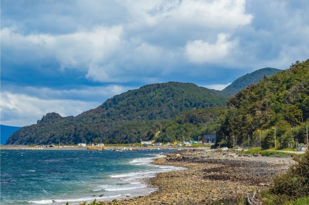 Vista de la costa de Puerto Almanza con el Canal Beagle, casas y cerros cubiertos de bosque, Tierra del Fuego