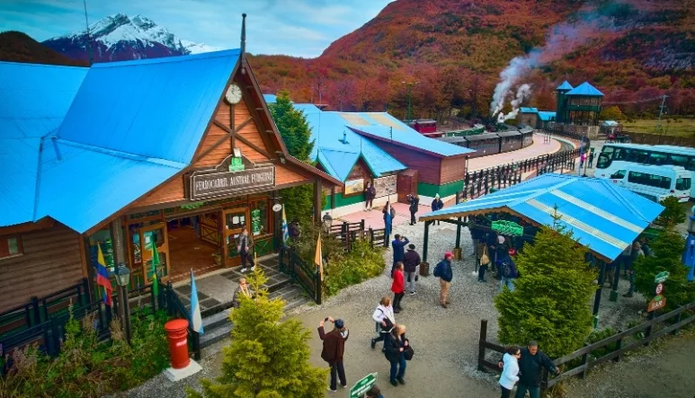 Vista aérea de la Estación Principal del Tren del Fin del Mundo en Ushuaia, con turistas y la montaña de fondo, Tierra del Fuego.