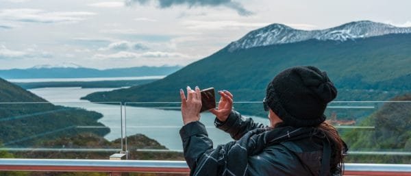 Una turista saca una foto con su celular al Lago Escondido desde el Mirador Paso Garibaldi en Ushuaia.
