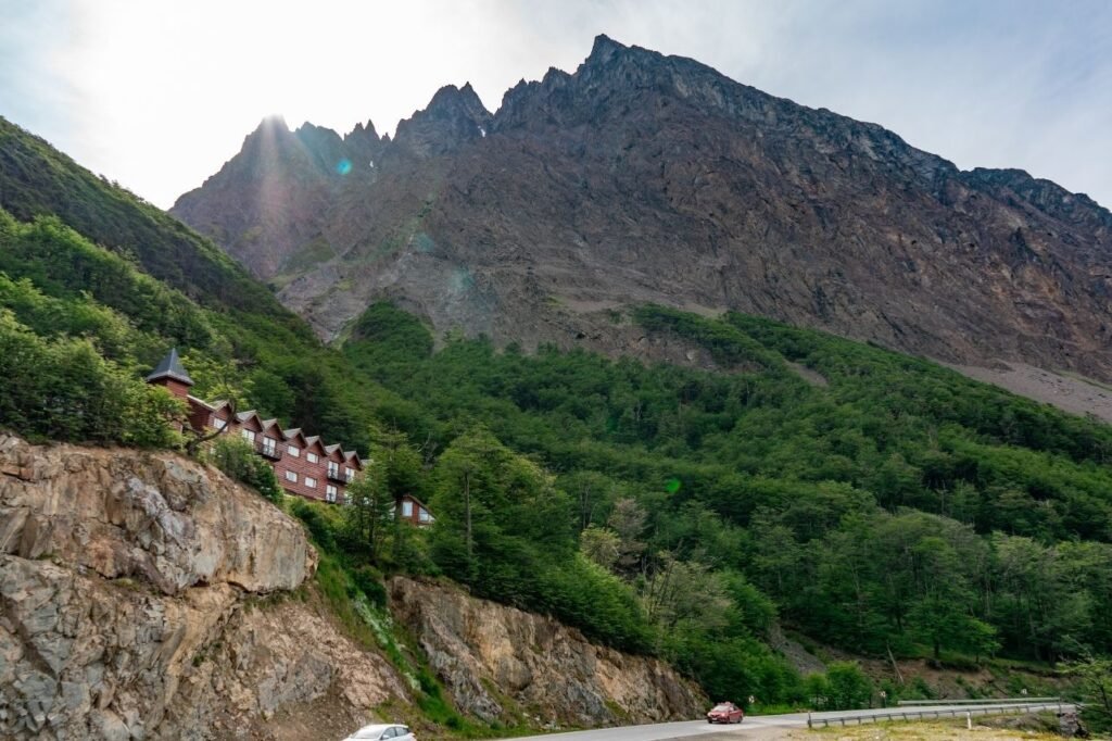 Monte Olivia con bosque de lengas sobre la ruta en Tierra del Fuego, con el hotel Bagu de madera en la ladera durante la travesía 4x4