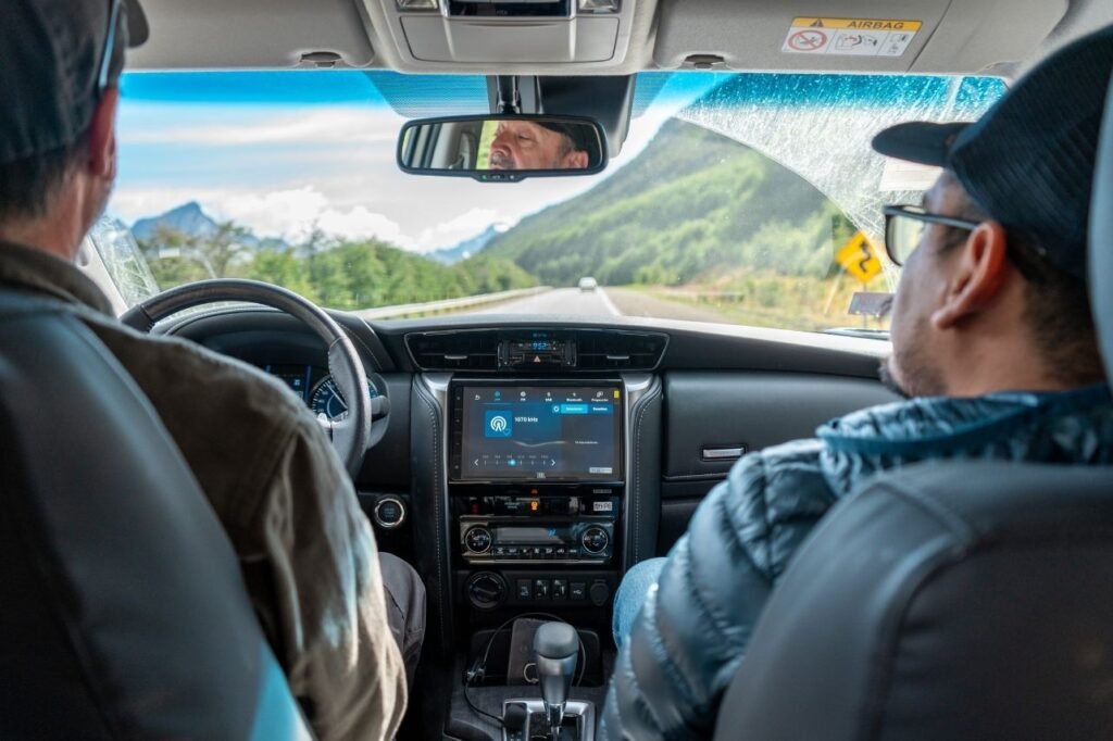 Vista desde el asiento trasero de una camioneta 4x4 con conductor y copiloto, mientras avanzan por una ruta de montaña en Tierra del Fuego.