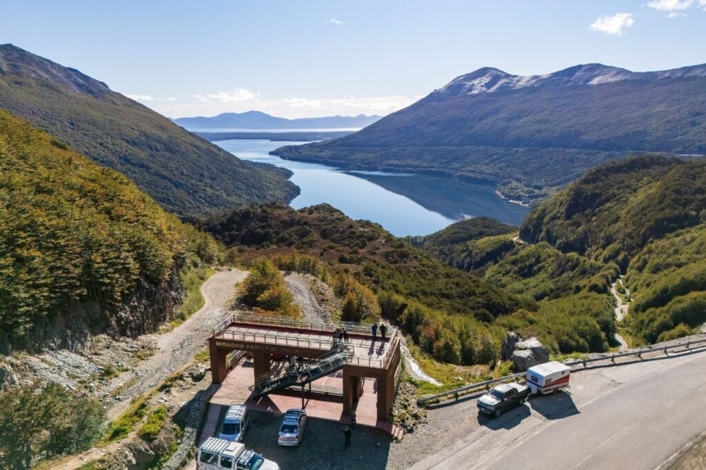 Vista aérea del Mirador Paso Garibaldi junto a la ruta, con el Lago Escondido y montañas con bosque y nieve al fondo en Tierra del Fuego.