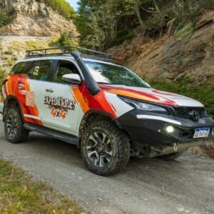Camioneta Toyota 4x4 de Expediciones 4x4 con parrilla y snorkel sobre un camino de ripio junto a paredes de roca y bosque en Tierra del Fuego.