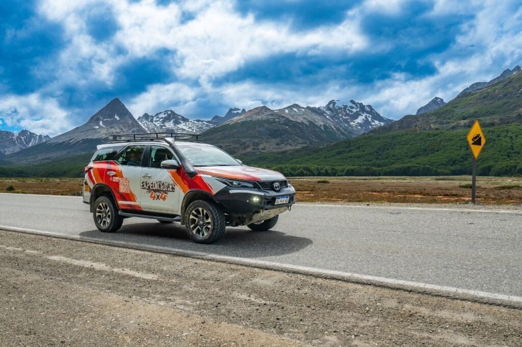 Camioneta Toyota Hilux ploteada de Aswalek Expediciones circulando por la Ruta 3 frente a la Cordillera de los Andes en Ushuaia.