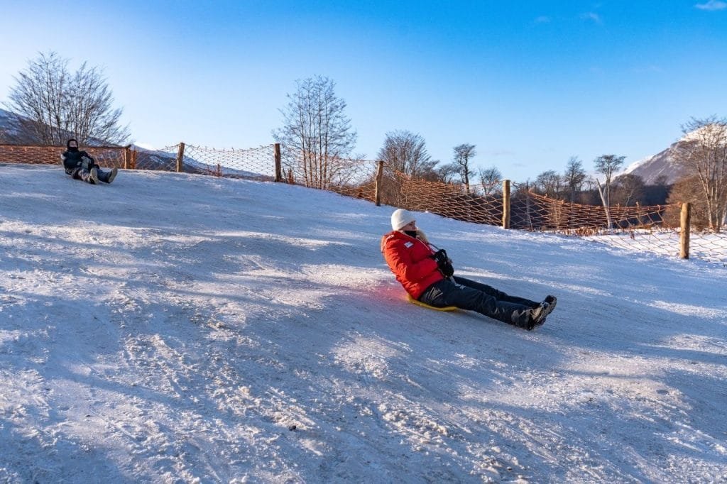 Persona deslizándose en culipatín por una pendiente de nieve acondicionada en Park Austral.