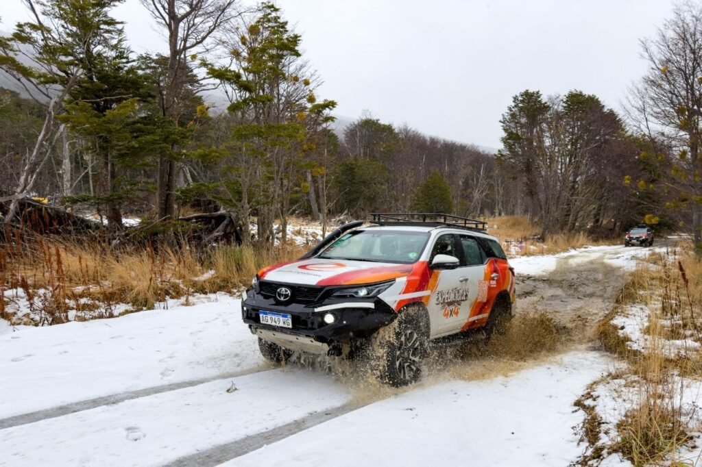 Vehículo 4x4 de expedición cruzando un terreno con nieve y charcos de barro en Ushuaia.
