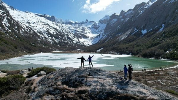 Pareja disfrutando la vista panorámica de la Laguna Esmeralda congelada y montañas nevadas durante el Trekking Laguna Esmeralda