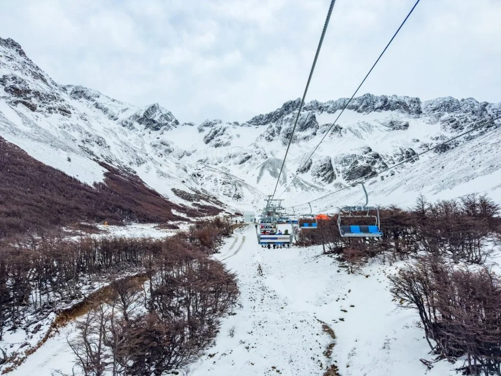 Vista panorámica desde la aerosilla del Glaciar Martial, Ushuaia, mostrando la subida por un valle nevado hacia las montañas andinas bajo un cielo nublado.