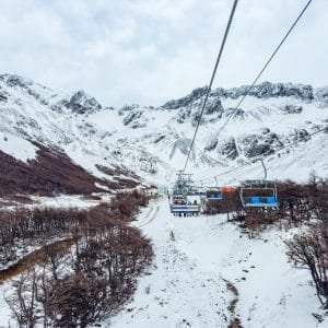 Vista panorámica desde la aerosilla del Glaciar Martial, Ushuaia, mostrando la subida por un valle nevado hacia las montañas andinas bajo un cielo nublado.